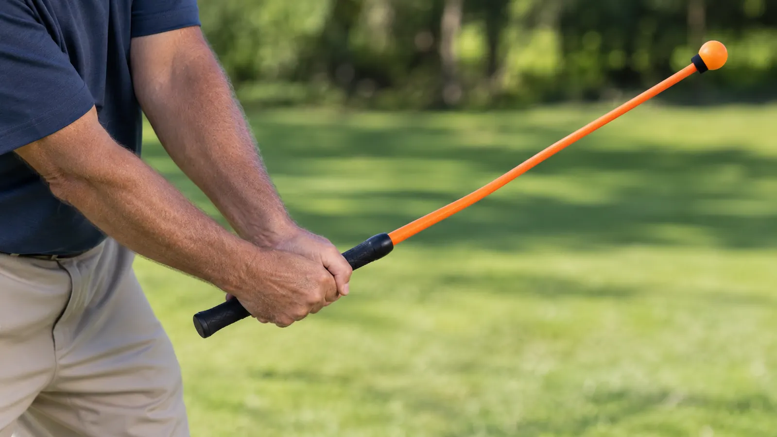 Close view of a golfer's hands gripping a flexible swing trainer while taking a practice swing on a lawn